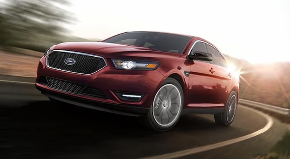 A red 2019 Ford Taurus driving on a sunny open road.