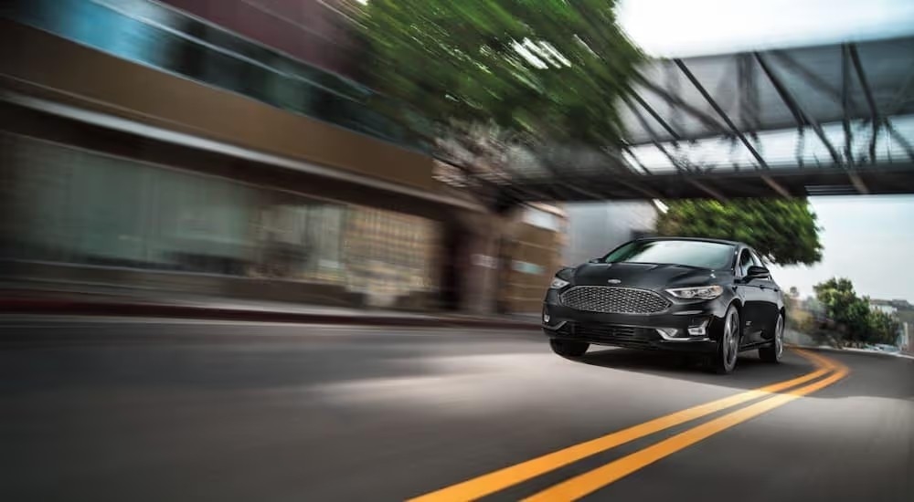 A black 2020 Ford Fusion Energi Titanium speeding through a city.