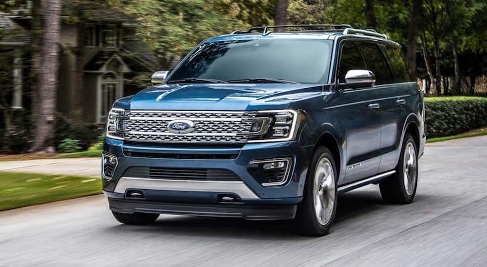 A blue 2020 Ford Expedition driving on a wooded residential street