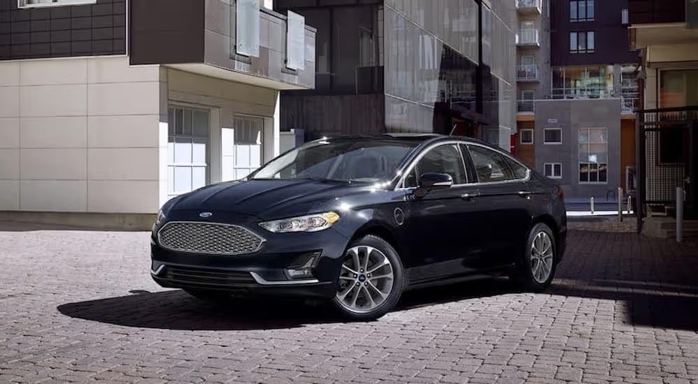 A black 2020 Ford Fusion parked on a modern industrial city street