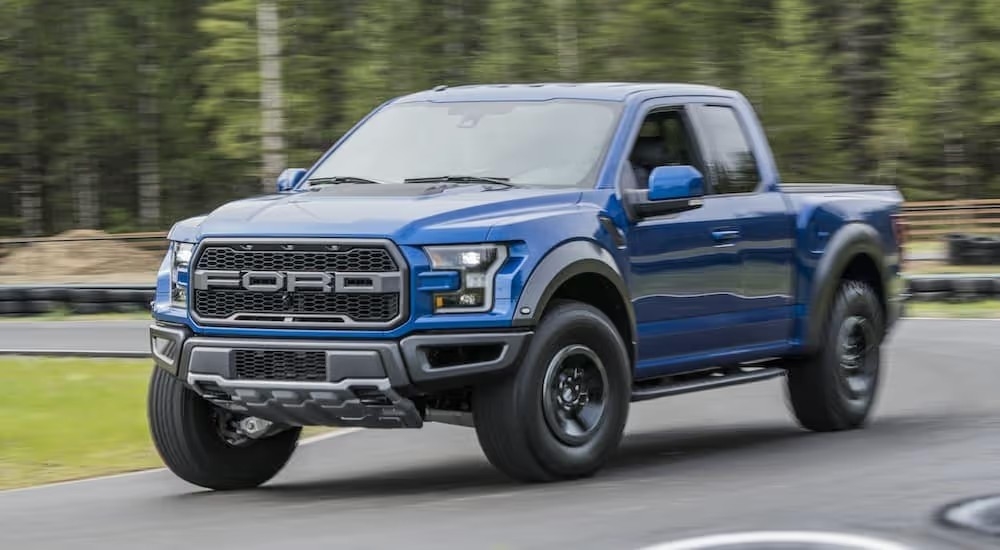 A blue 2017 Ford F-150 Raptor driving fast on a track