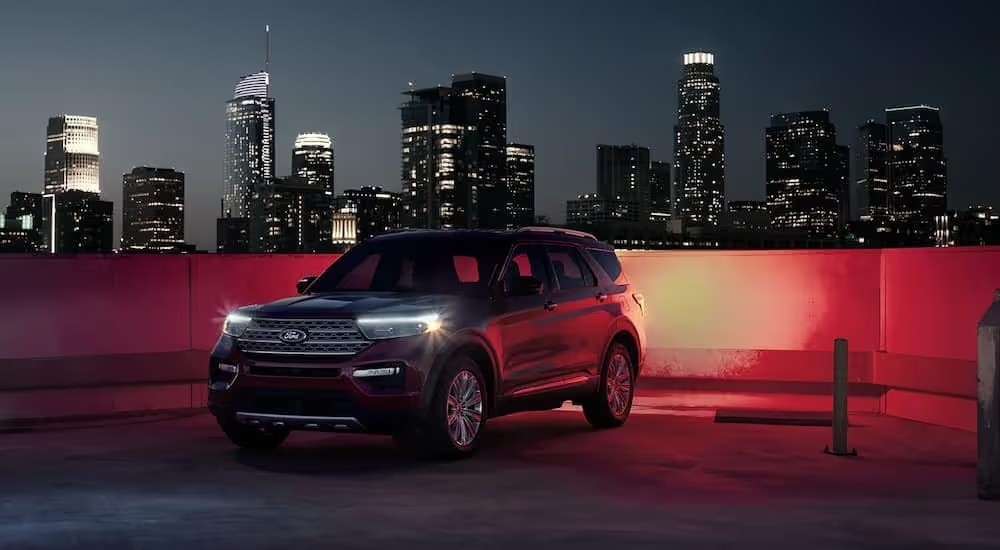 A black 2022 Ford Explorer Hybrid on a rooftop parking area overlooking a city skyline at night
