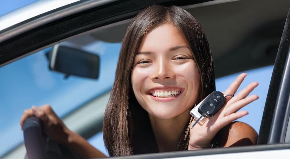 A teen is shown holding a car key at a used car lot near you.