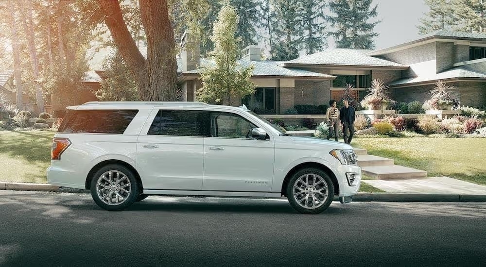 A white 2018 Ford Expedition Platinum is shown from the side parked in front of a house.