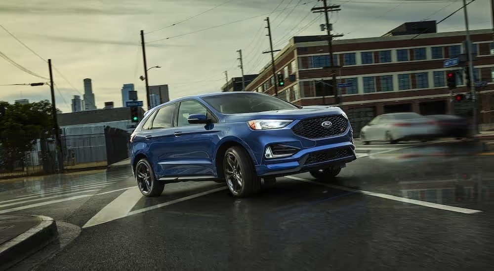 A blue 2018 Ford Edge is shown driving through an intersection after visiting a Murfreesboro used Ford dealership.
