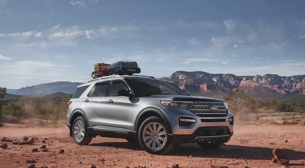 A silver 2021 Ford Explorer Platinum with a roof rack is shown parked in the desert.