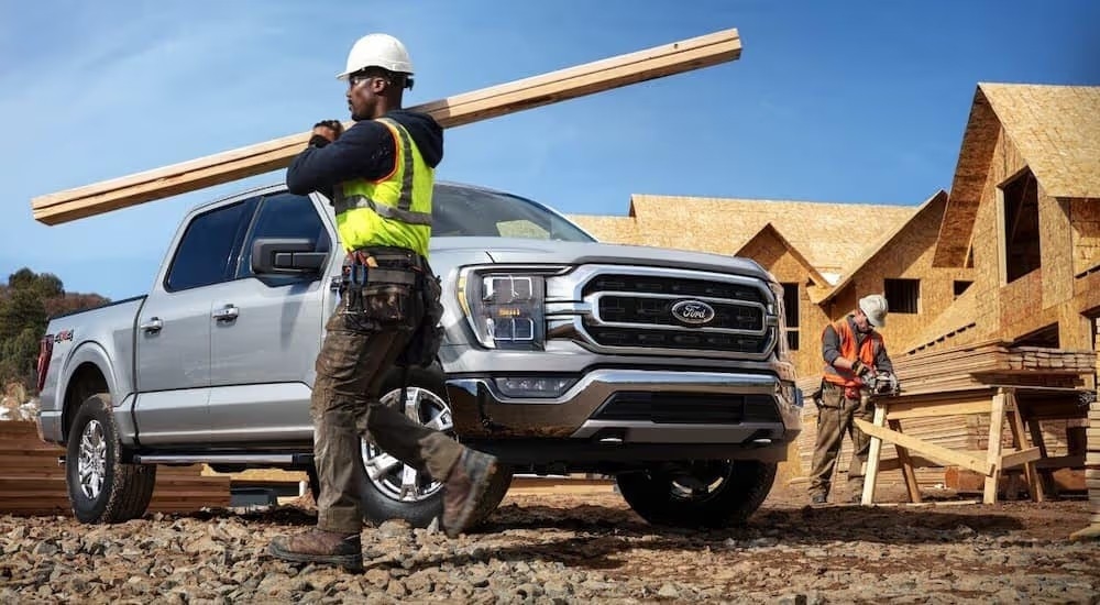 A construction worker is shown walking in front of a silver 2021 Ford F-150 XLT.