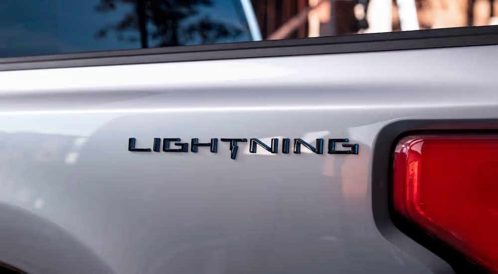 A close up shows the 'Lightning' lettering on the bed of a silver 2022 Ford F-150 Lightning.