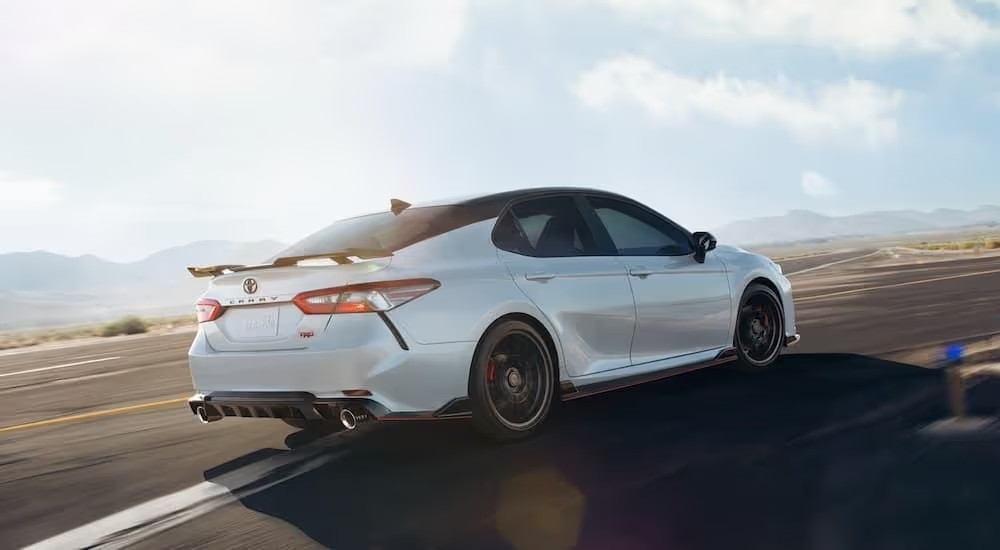 A white 2020 Toyota Camry TRD is shown form the side driving on an open road.