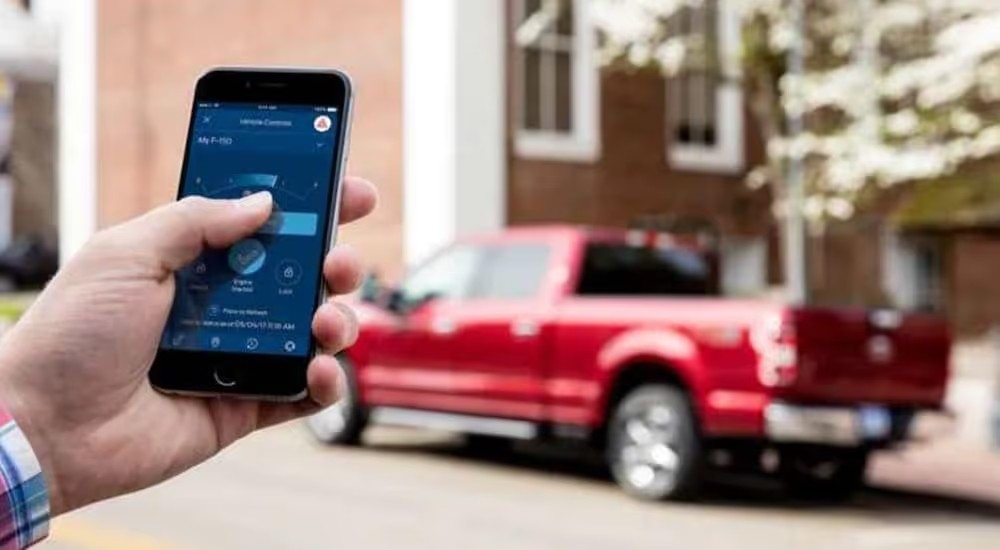 A man is using his smartphone to connect with his Ford F-150 after leaving the Ford dealership in Shelbyville.