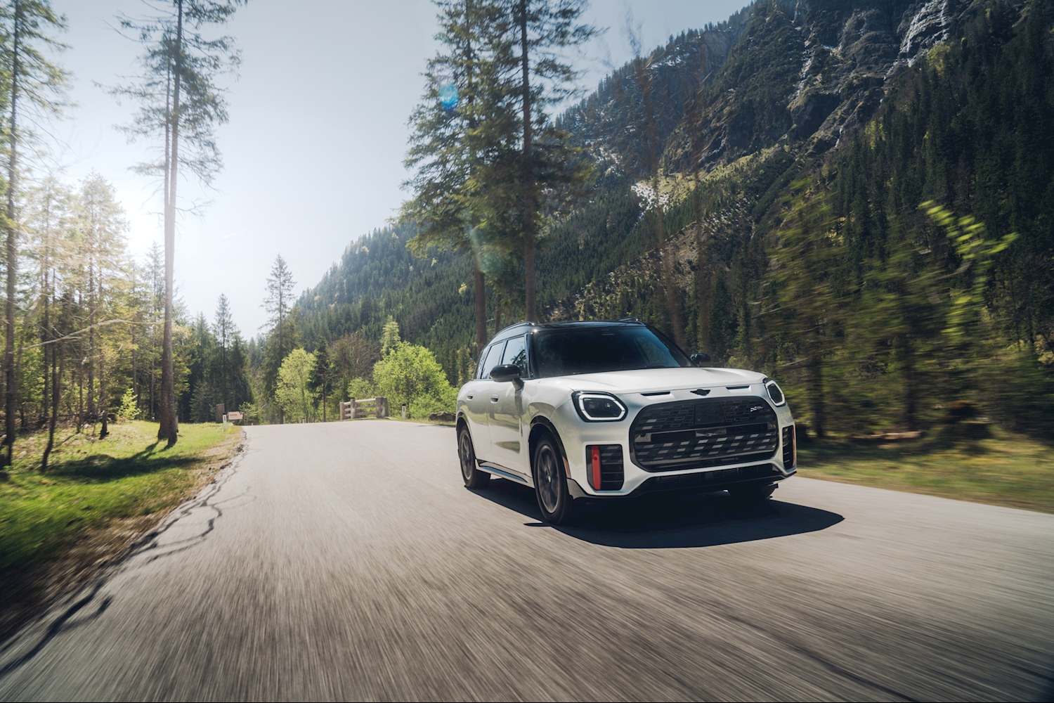 White MINI Countryman driving on a scenic mountain road, front three-quarter view