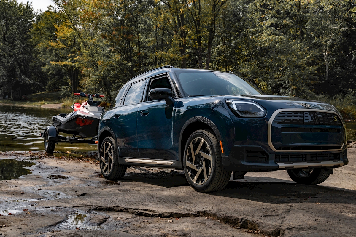 Dark blue MINI Countryman S ALL4 towing a personal watercraft on a trailer at a lakeside boat ramp