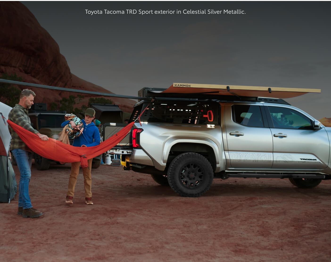 Side-profile view of a Celestial Silver Metallic Toyota Tacoma TRD Sport with an awning at a desert canyon.