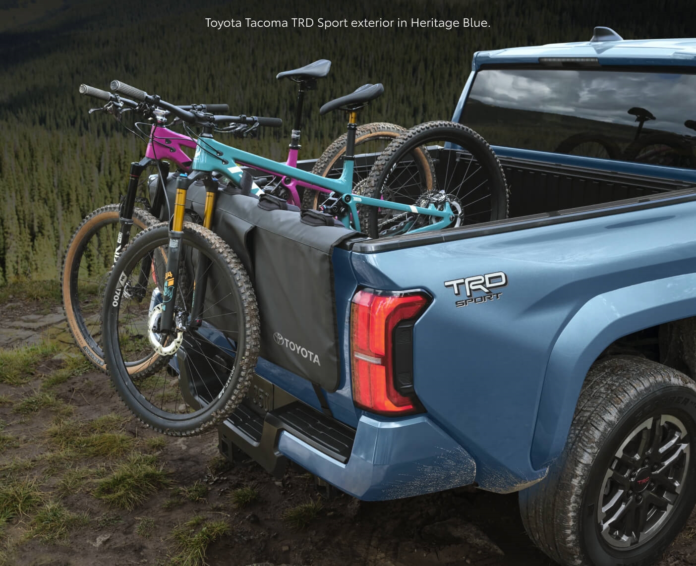 Rear-quarter view of a Heritage Blue Toyota Tacoma TRD Sport carrying mountain bikes.