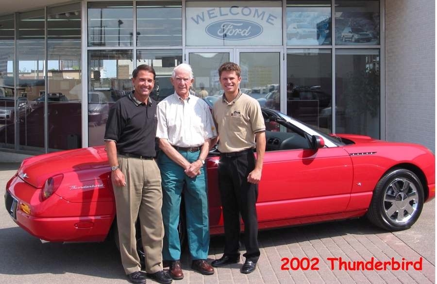 Three generations of the Dahl family standing in front of a red Thunderbird