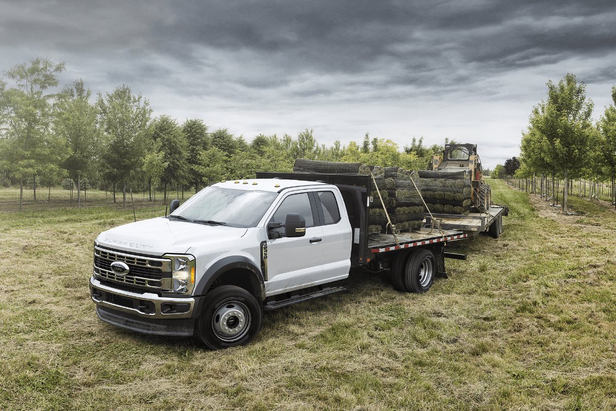 Ford Super Duty chassis cab with flatbed hauling equipment in an agricultural work setting 