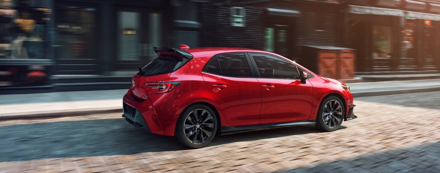 Red 2021 Toyota Corolla driving down a road.