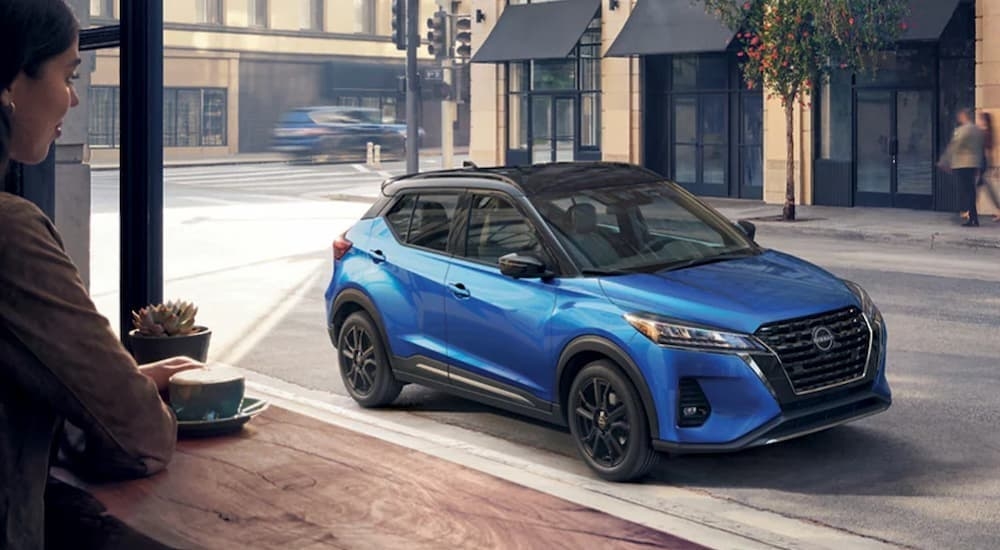 A blue 2023 Nissan Kicks parked in a city.