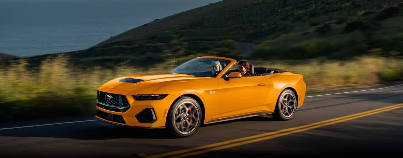 A yellow 2026 Ford Mustang GT driving on a highway.