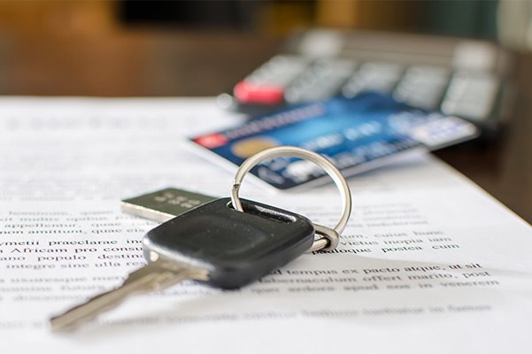 Credit card and car key sitting on top of paperwork