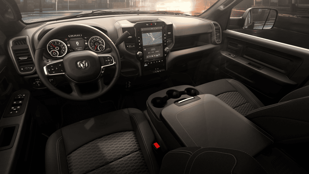 2026 Ram Heavy Duty interior in Margate FL with RAM-branded steering wheel, vertical touchscreen infotainment with navigation, analog instrument cluster, and black cloth seating