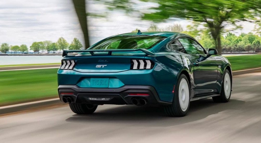 A green 2026 Ford Mustang driving fast on a street.