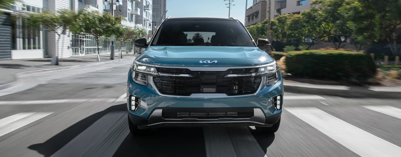 Front of a blue 2026 Kia Seltos driving down a city street.