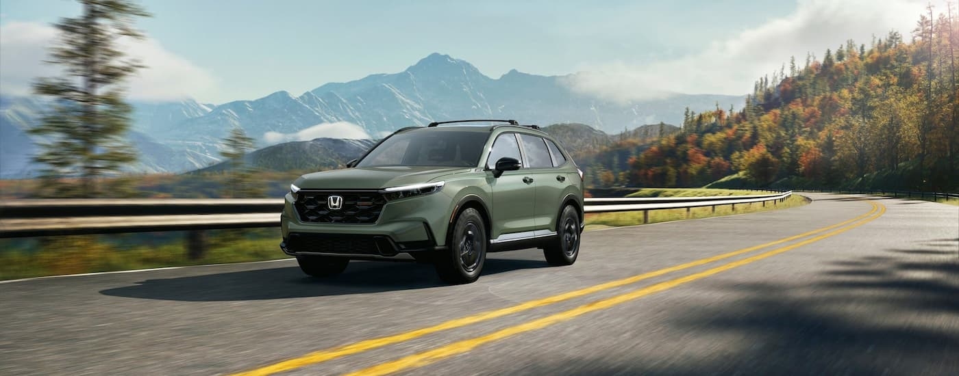Green 2026 Honda CR-V driving down a road.