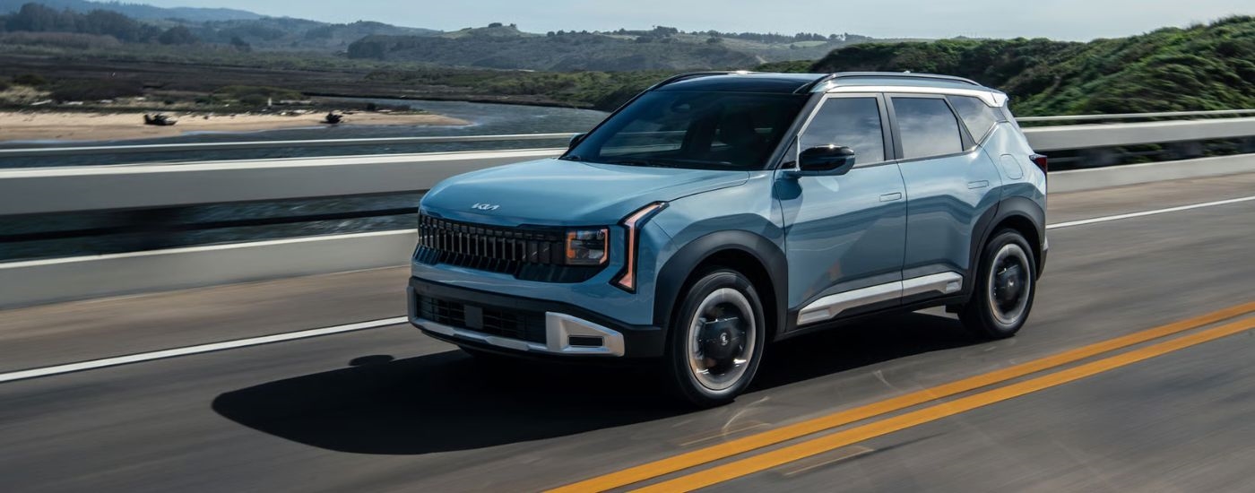 A blue 2027 Kia Seltos driving over a bridge.