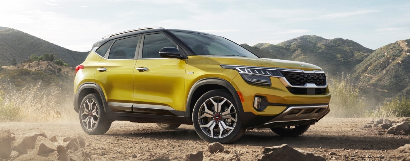 A yellow 2021 Kia Seltos parked off-road.