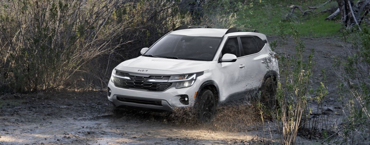 A white 2024 Kia Seltos driving into mud.