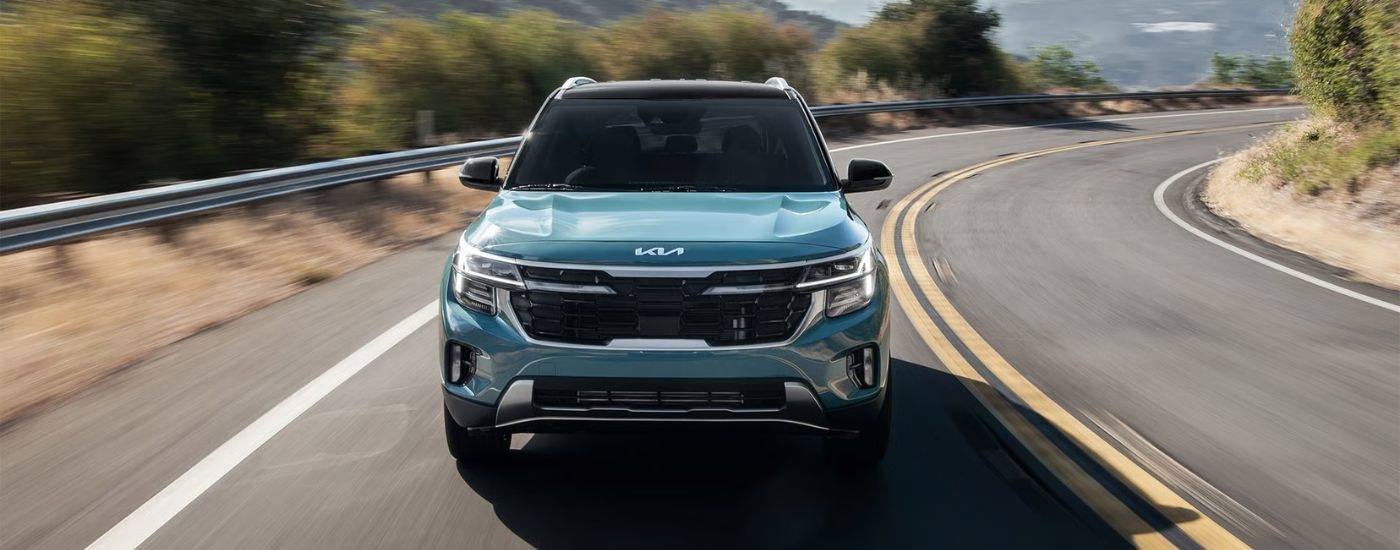 Blue 2026 Kia Seltos front view driving on a paved road.