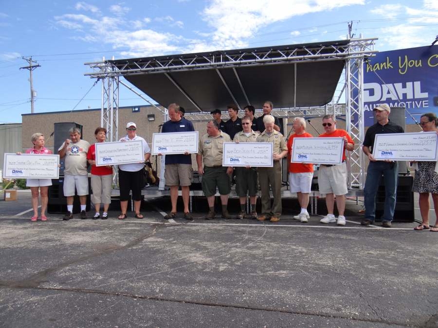Line of community representatives holding oversized checks