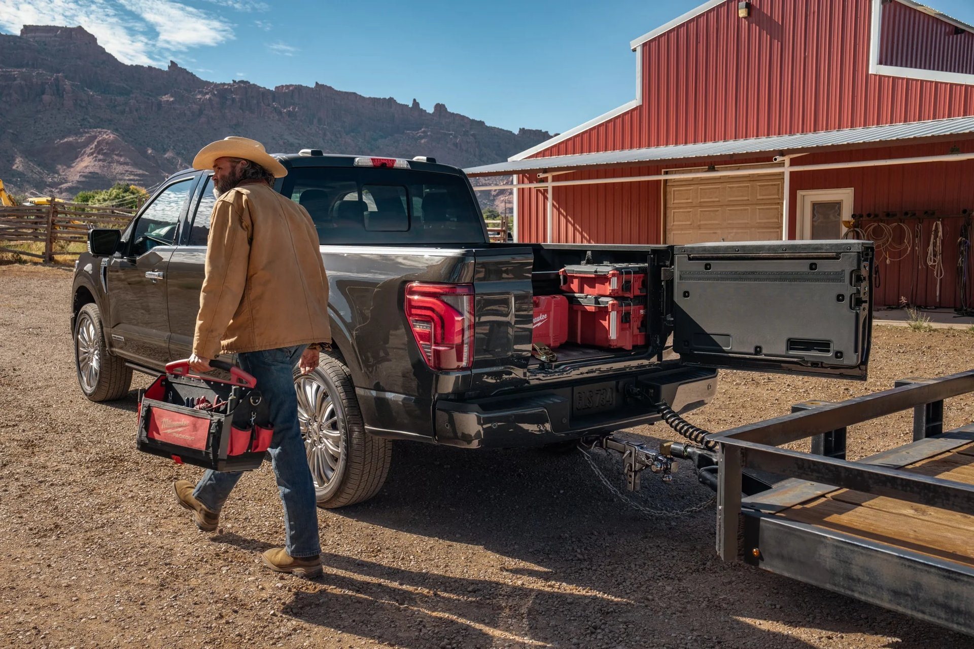 Loading gear into the bed of a 2026 Ford F-150 with a trailer hitched behind