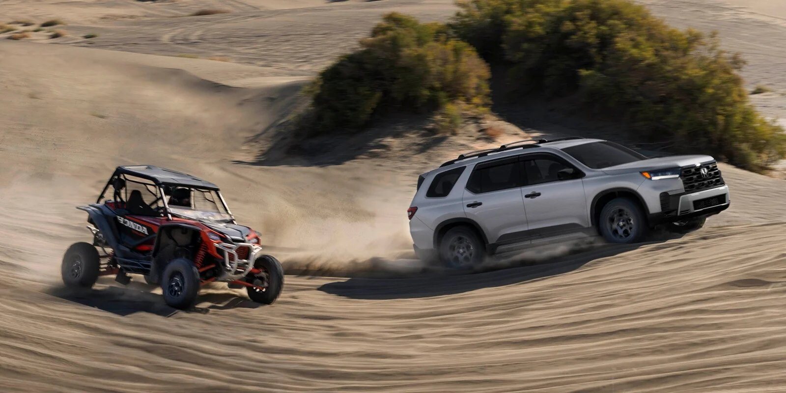 2026 Honda Pilot TrailSport driving alongside a Honda side-by-side on sand