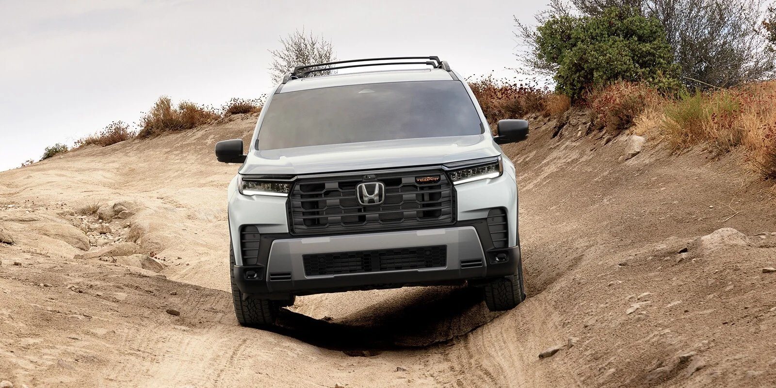 2026 Honda Pilot TrailSport with all-terrain tires and orange TrailSport grille badge