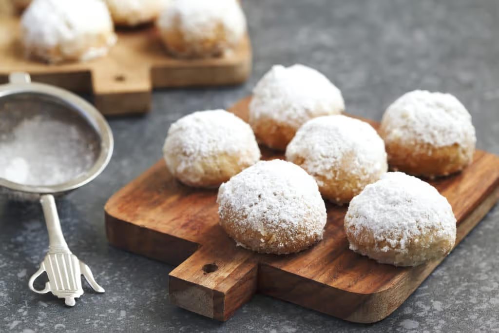 cookies in powdered sugar on a wooden cutting board