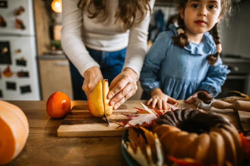 Little girl assisting to mother in kitchen