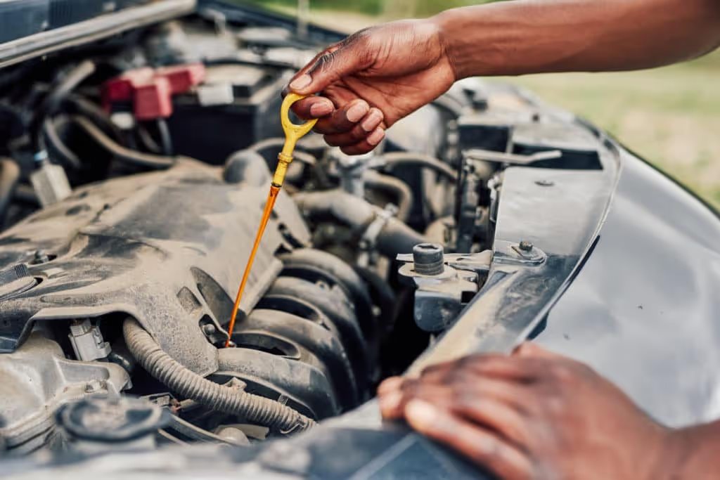 hands under hood of car checking oil