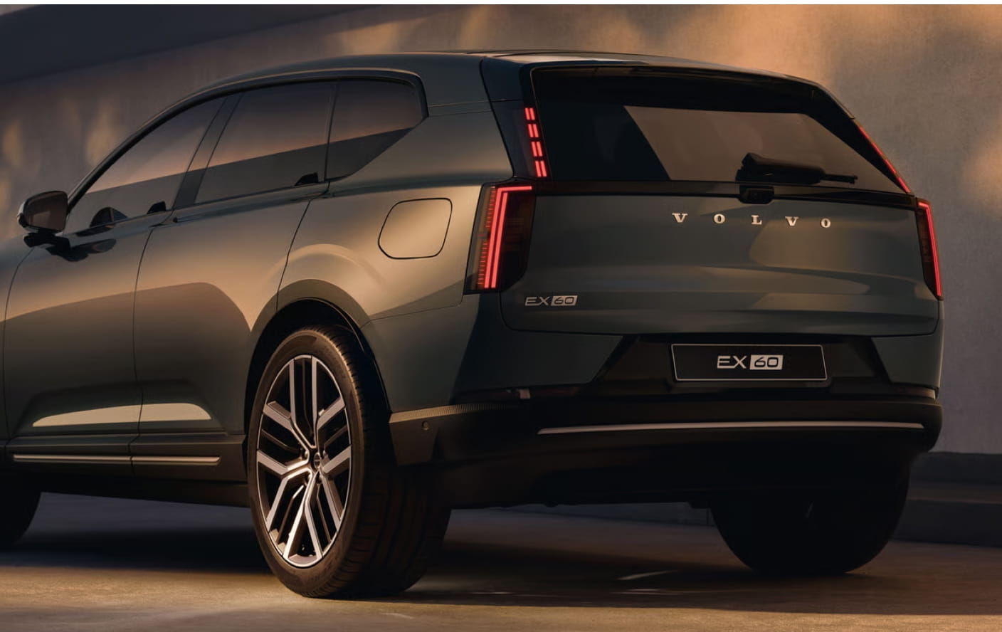 Volvo EX60 shown from a rear three-quarter angle with illuminated vertical taillights.