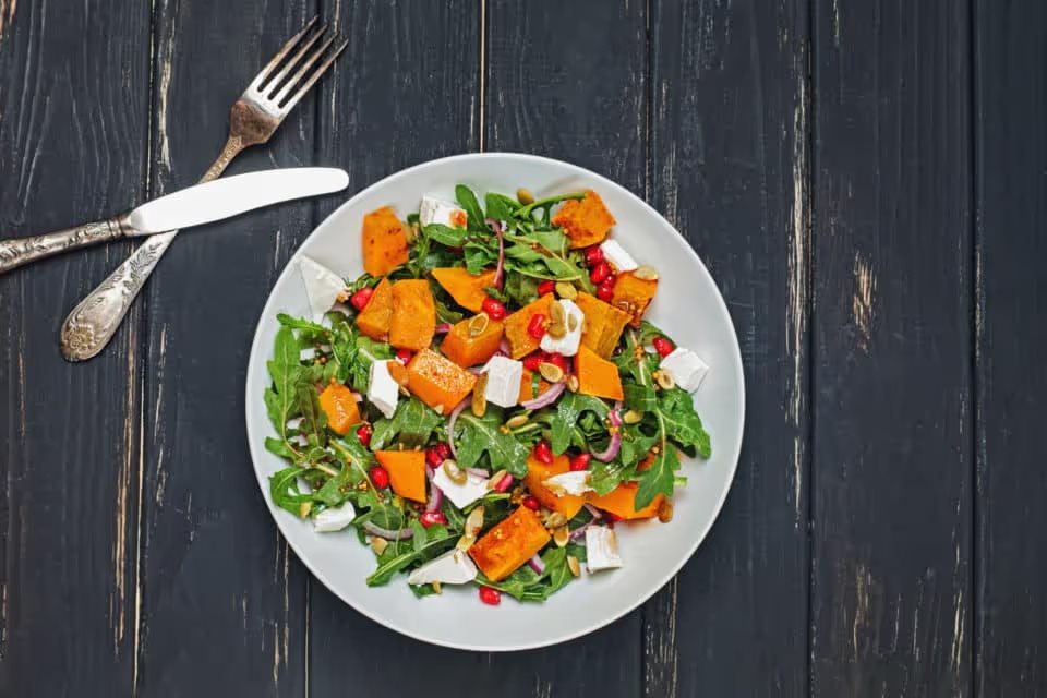 Salad with greens, sweet potato, and pomegranate seeds