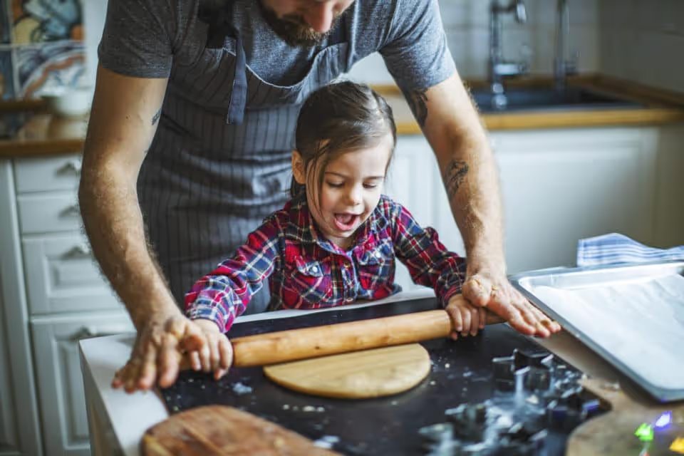 Father and daughter rolling out dough for Christmas cookies