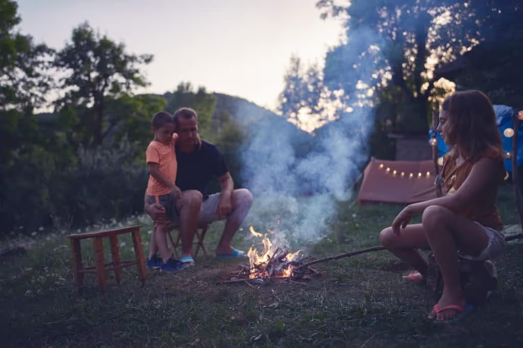 Father with children making a camping fire in the backyard.