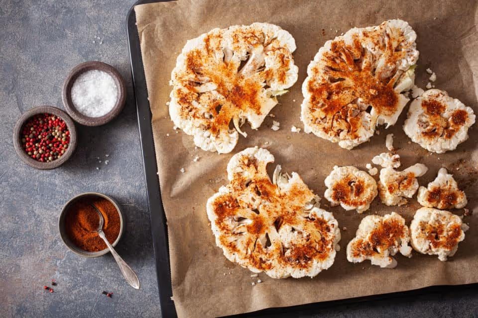 roasted cauliflower steaks with spice on baking tray. plant based meat substitute