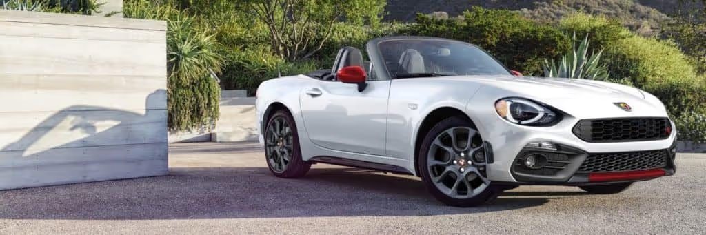 white FIAT Spider in driveway with trees in background