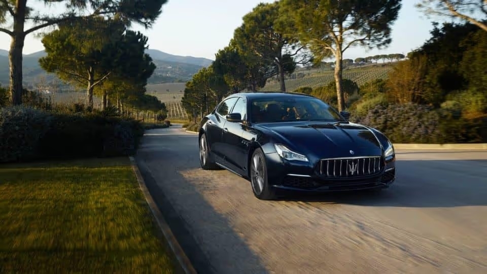 Black Maserati Quattroporte driving along a tree-lined road