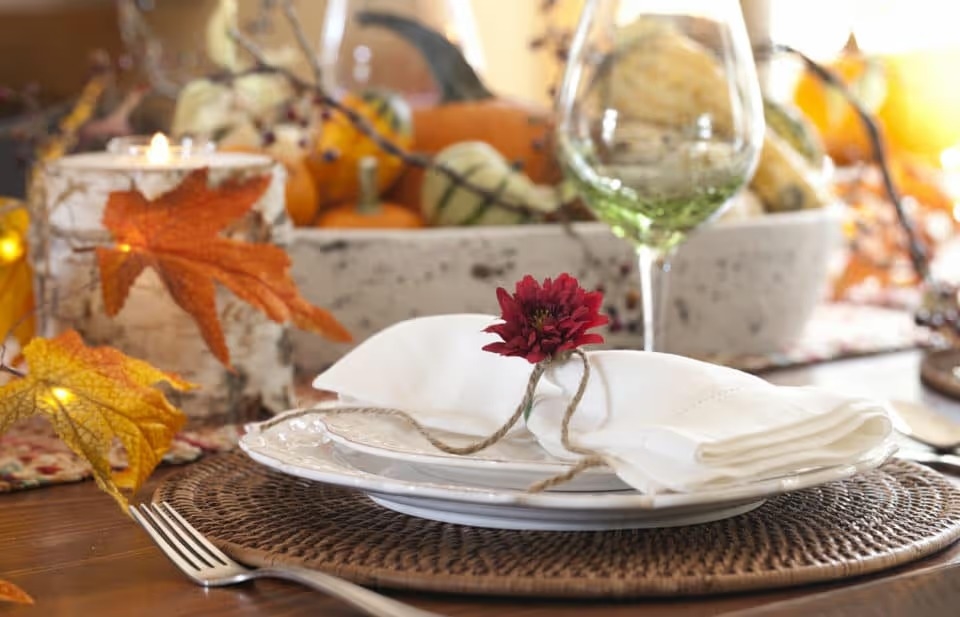 Autumn Thanksgiving holiday dining table place setting with a centerpiece of pumpkins and gourds