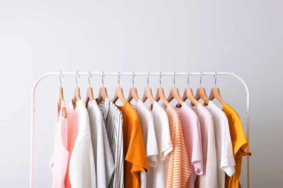 pink, white and orange clothes on a white rack; capsule wardrobe.