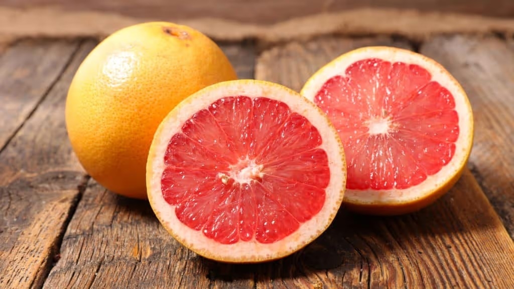 whole and sliced grapefruit on wood background