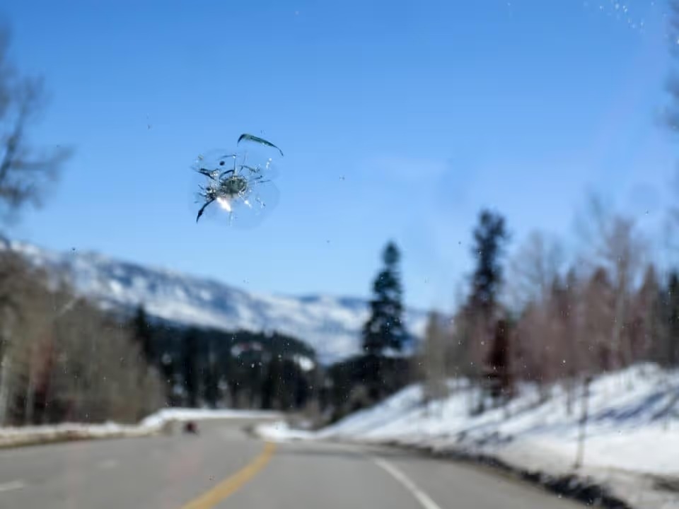 Chipped windshield with road and snow covered mountains